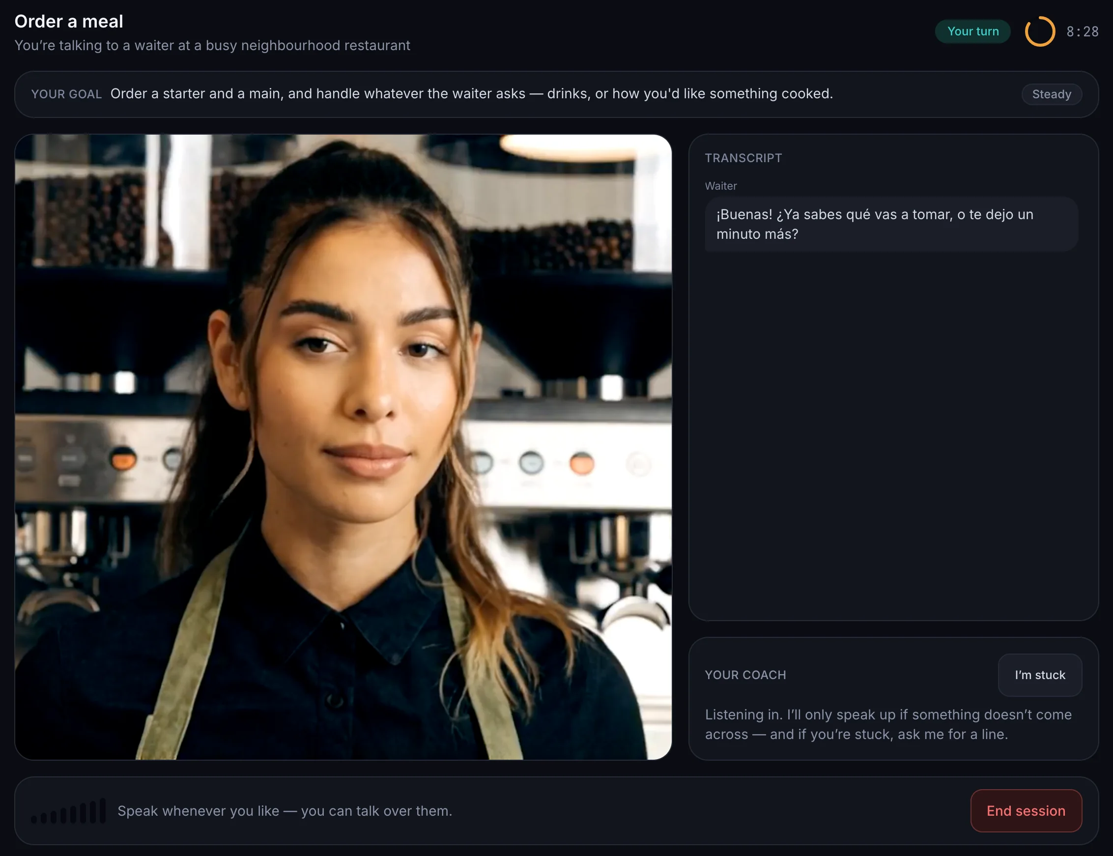 A banter practice session in Spanish on the Studio plan. banter’s AI video partner, a waiter in a green apron standing in front of an espresso machine, is on a live video call. Beside her, the transcript shows her opening line: “¡Buenas! ¿Ya sabes qué vas a tomar, o te dejo un minuto más?” Above the call the learner’s goal reads “Order a starter and a main”, a status chip says “Your turn”, and a coach panel below offers help if they get stuck.
